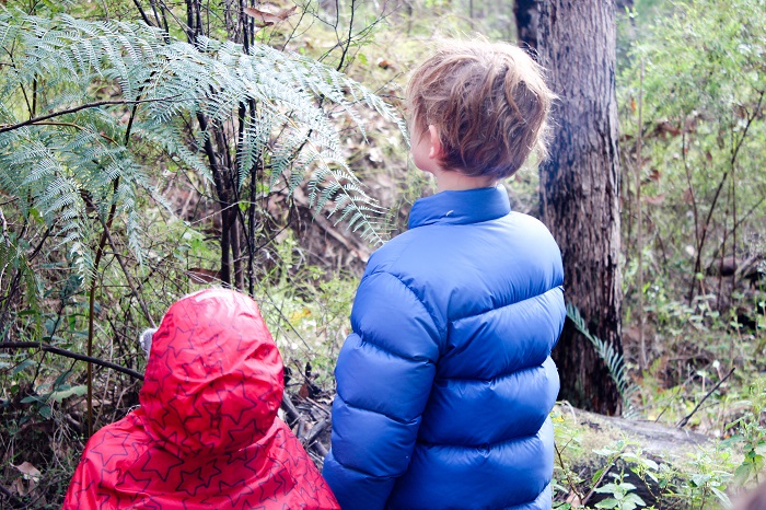 two children looking into bush