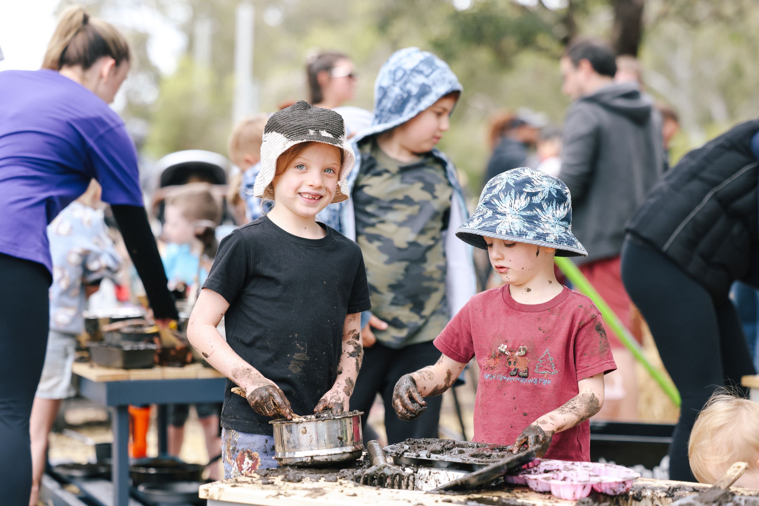 Two kids playing at a mud kitchen.
