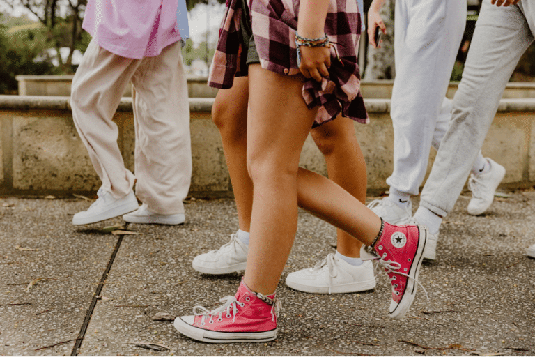 Group of girls' feet walking on footpath.